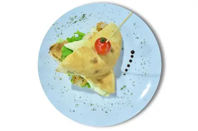 a plate with a sandwich with a tomato on it at Hotel Vrata Bosne in Velika Kladuša