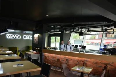 two people standing at the counter of a restaurant at Hotel Vrata Bosne in Velika Kladuša