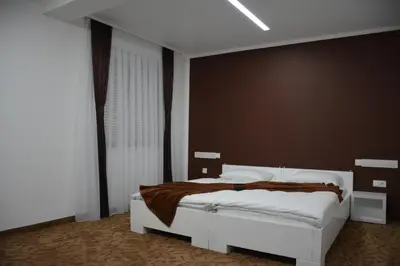 a bedroom with a white bed with a brown blanket at Hotel Vrata Bosne in Velika Kladuša