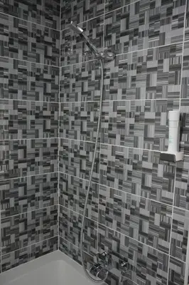 a shower in a bathroom with a tile wall at Hotel Vrata Bosne in Velika Kladuša
