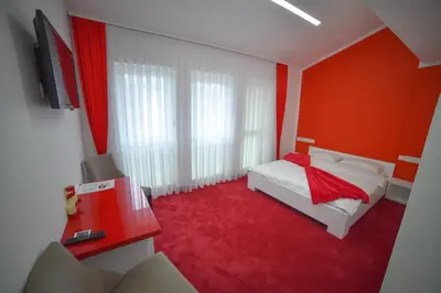 a red bedroom with a white bed and red carpet at Hotel Vrata Bosne in Velika Kladuša