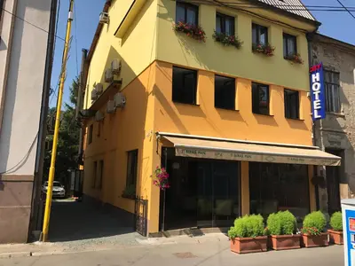 a yellow building with plants in front of it at Heartland City B&B in Tuzla