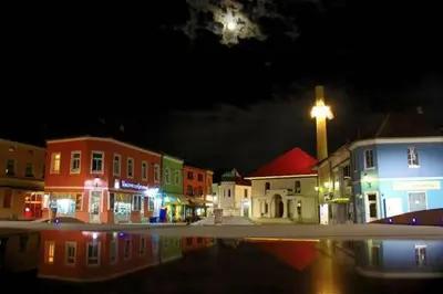 a small town at night with a reflection in the water at Heartland City B&B in Tuzla