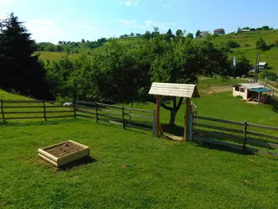 a field with a fence and a sign in the grass at Forest Lodge on the Pyramid in Visoko