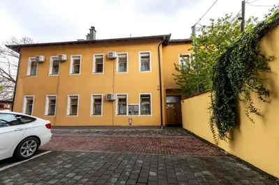 a yellow building with a car parked in front of it at Apartments Villa Kobilj in Banja Luka