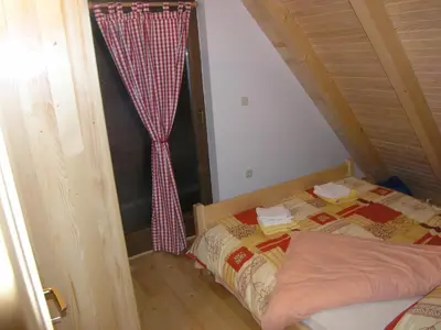 a small bedroom with a bed and a curtain at Planinska kuća Kupres in Kupres