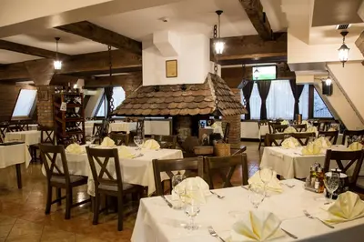 a restaurant with white tables and chairs and a fireplace at Hotel Babino Brdo in Derventa