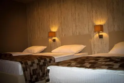 two beds in a room with lights on the wall at Hotel Palazzo in Gornji Vakuf