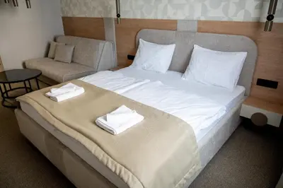 a bedroom with a large bed with white sheets and a chair at Hotel Palazzo in Gornji Vakuf