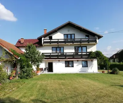 a large white house with a large yard at Apartments Kenedy in Kiseljak