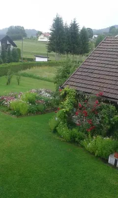 a view of a garden with flowers and a house at Apartments Kenedy in Kiseljak