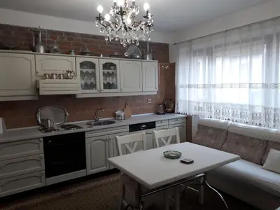 a kitchen with white cabinets and a table and a chandelier at Apartment Sun in Visoko