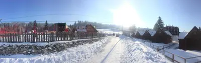 a snow covered street with houses and a fence at Apartman Ena in Vlasic