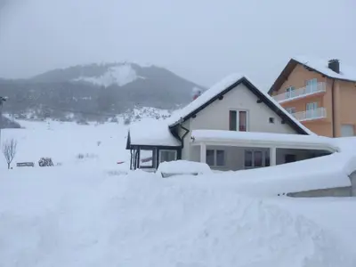 a house covered in snow in front at Apartments Herc in Kupres