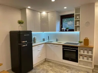 a kitchen with a black refrigerator and white cabinets at Holiday Home Oaza Mira in Visoko