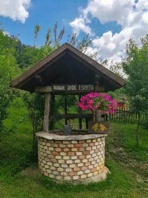 a sign on top of a brick structure with flowers at Holiday Home Nektar Park in Bihać