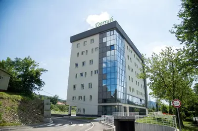 a tall white building with a sign on top of it at University Hotel Dorrah in Tuzla