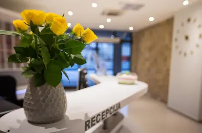 a vase filled with yellow roses sitting on a counter at University Hotel Dorrah in Tuzla
