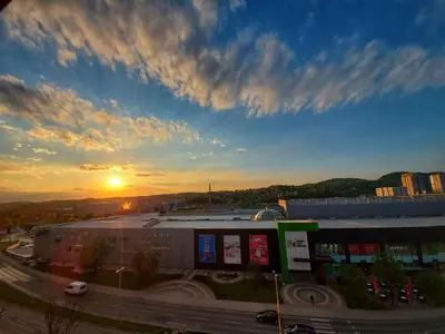 a sunset over a city with a parking lot and a building at University Hotel Dorrah in Tuzla