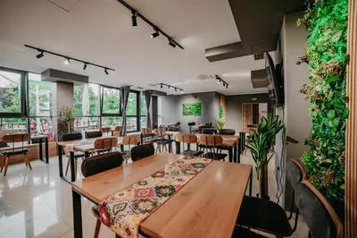 a restaurant with wooden tables and chairs and plants at University Hotel Dorrah in Tuzla