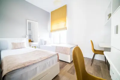a small bedroom with two beds and a desk at University Hotel Dorrah in Tuzla