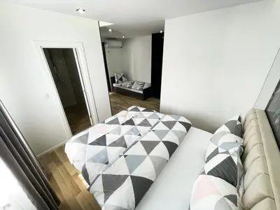 a bedroom with a bed with a checkered pillow at Apartmani Mila in Laktaši