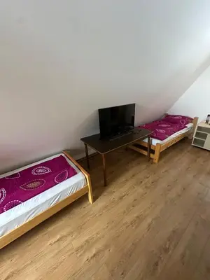 two beds in a room with a table and a tv at Vikendica Anja in Vlasic