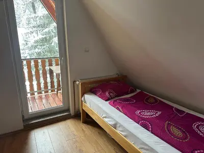 a small bed in a room next to a window at Vikendica Anja in Vlasic