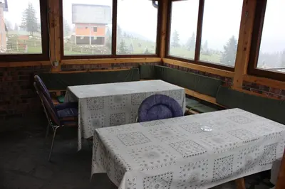 two tables and chairs in a room with windows at Apartments Zoni in Vlasic