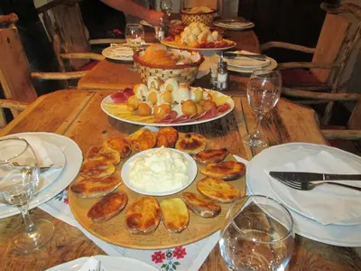 a wooden table with plates of food and glasses of wine at Etno Selo Dodig in Drvar
