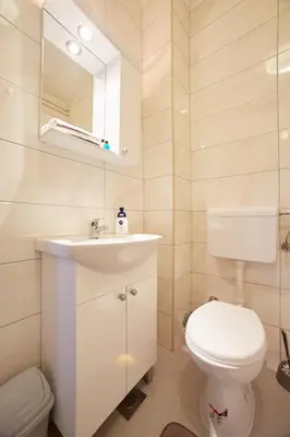 a bathroom with a toilet and a sink and a mirror at Central Tuzla apt - free parking in Tuzla