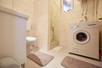 a bathroom with a toilet and a washing machine at Central Tuzla apt - free parking in Tuzla