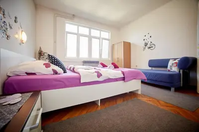 a bedroom with a large bed and a blue couch at Central Tuzla apt - free parking in Tuzla