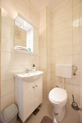 a white bathroom with a toilet and a sink at Central Tuzla apt - free parking in Tuzla
