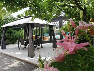 a gazebo with a table and chairs and flowers at Deluxe Villa Coast River Sarajevo in Visoko