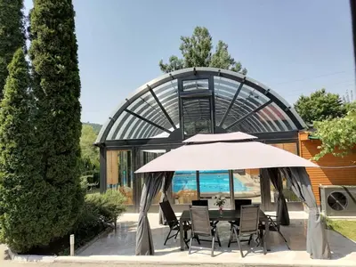 a table with an umbrella in front of a building at Deluxe Villa Coast River Sarajevo in Visoko