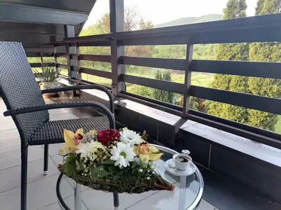 a table with a bouquet of flowers on a balcony at Deluxe Villa Coast River Sarajevo in Visoko