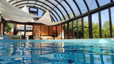 a swimming pool with a glass ceiling and a building at Deluxe Villa Coast River Sarajevo in Visoko