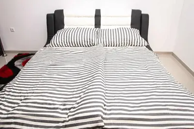 a bed with a black and white blanket on it at Motel Medium in Bihać
