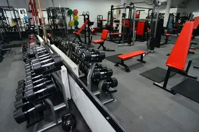 a gym with several rows of machines and red chairs at Motel Medium in Bihać