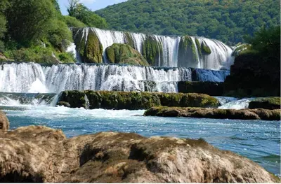 a waterfall in the middle of a river with rocks at Motel Medium in Bihać