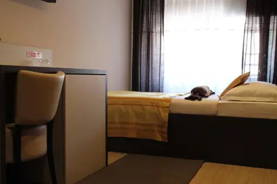 a dog laying on a bed in a bedroom at Motel Korzo in Bihać
