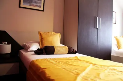 a bedroom with a bed with a yellow blanket on it at Motel Korzo in Bihać