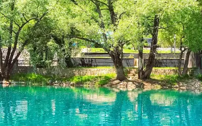 a pool of blue water with trees and a fence at Mila Holiday Home in Lohovo