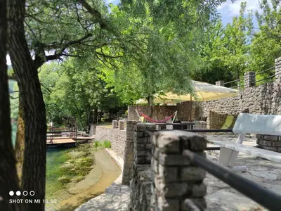 a stone wall with a bench and a tree at Mila Holiday Home in Lohovo