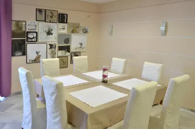 a dining room with a table and white chairs at Motel New Sanatron in Bosanski Novi