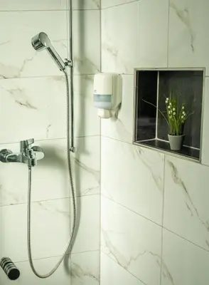 a shower in a bathroom with white marble walls at Swiss Plus Hotel in Bihać