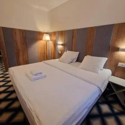 a large white bed with a pair of towels on it at Swiss Plus Hotel in Bihać