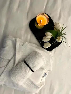 a black tray with a candle and flowers on a bed at Swiss Plus Hotel in Bihać