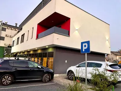 two cars parked in front of a building with a parking meter at Swiss Plus Hotel in Bihać